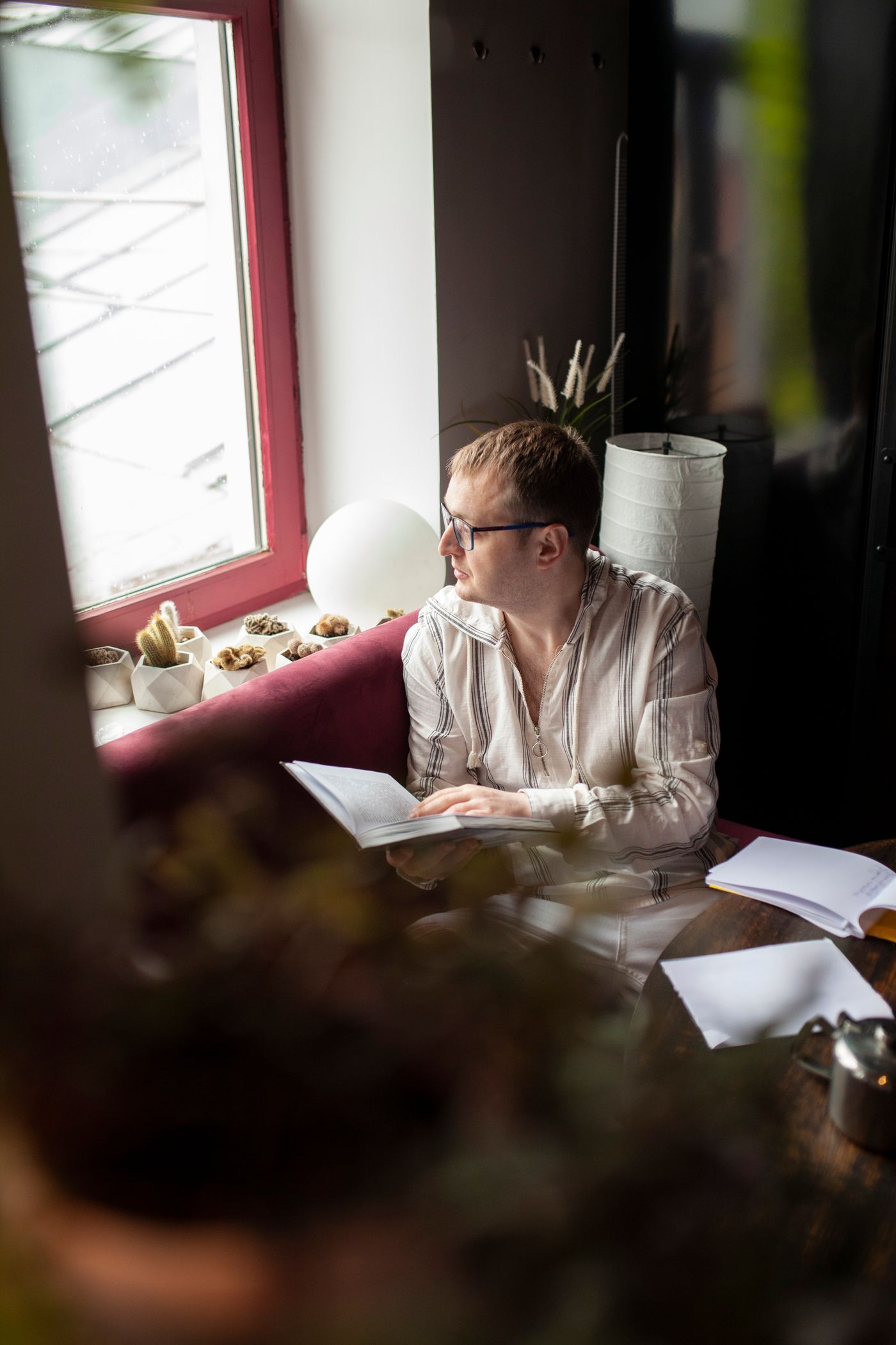 A person reading paperwork at a table in window light.