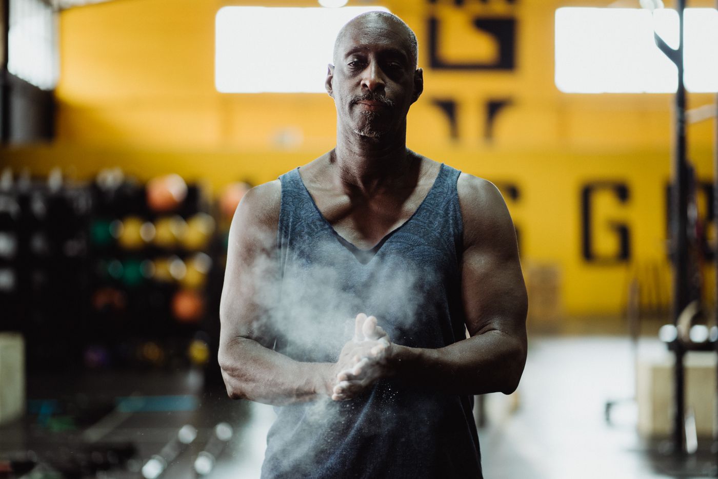 A man mid-forties in a cold-lit gym, composed after a workout.